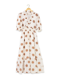 An off-white wrap-style midi dress with brown polka dots, featuring short puff sleeves, a ruffled collar, and a tiered skirt, hanging on a wooden hanger against a white background.