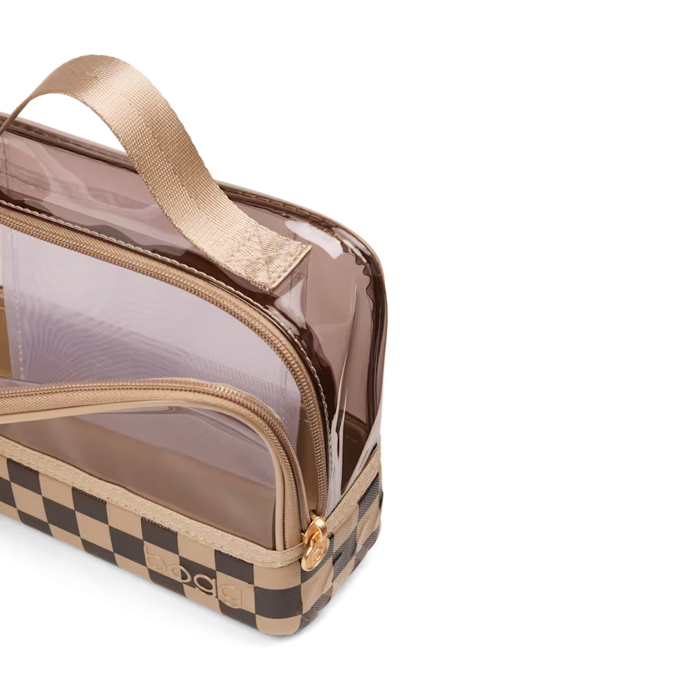 A clear plastic toiletry bag with a beige handle, gold zipper, and a brown and beige checkerboard patterned base, shown on a white background.