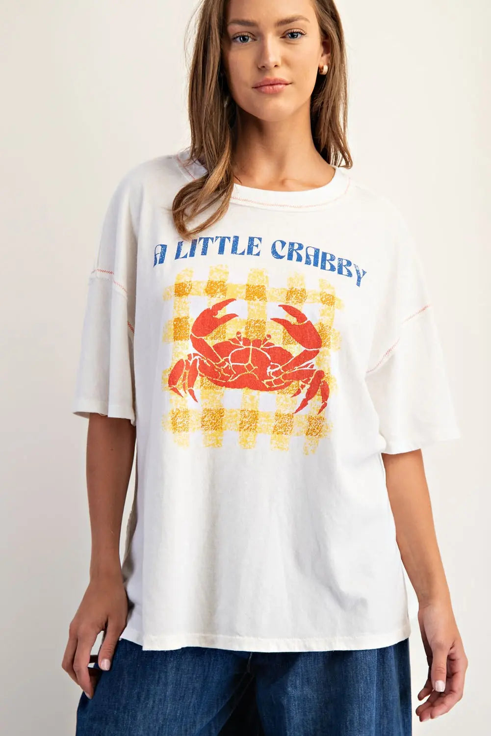 Woman wearing a white t-shirt with a red crab graphic and text on a plain background