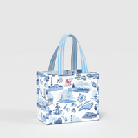 A small tote bag with blue and white striped handles, featuring a blue illustrated North Carolina landscape print on a white background, photographed against a light gray studio backdrop.