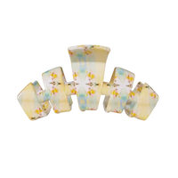 A retro-style multi-loop hair claw clip made of glossy, translucent resin with a pastel yellow, blue, and white marbled pattern and small yellow floral details, shown on a plain white background.