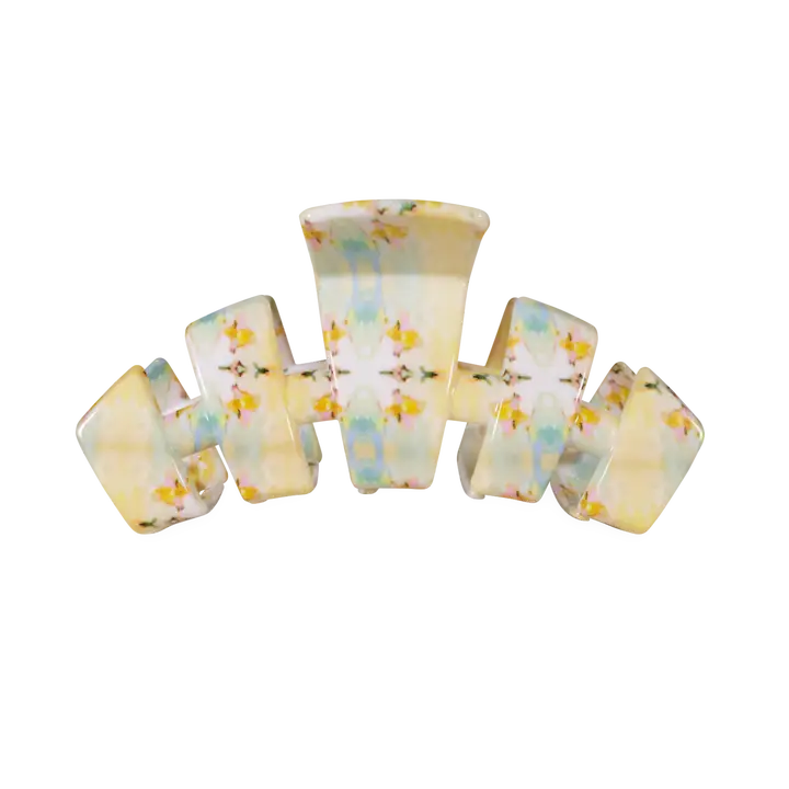 A retro-style multi-loop hair claw clip made of glossy, translucent resin with a pastel yellow, blue, and white marbled pattern and small yellow floral details, shown on a plain white background.