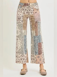 A person wearing patchwork wide-leg cropped pants with a multicolor floral and abstract print in beige, blue, pink, and brown tones, paired with flat tan shoes against a plain light background.